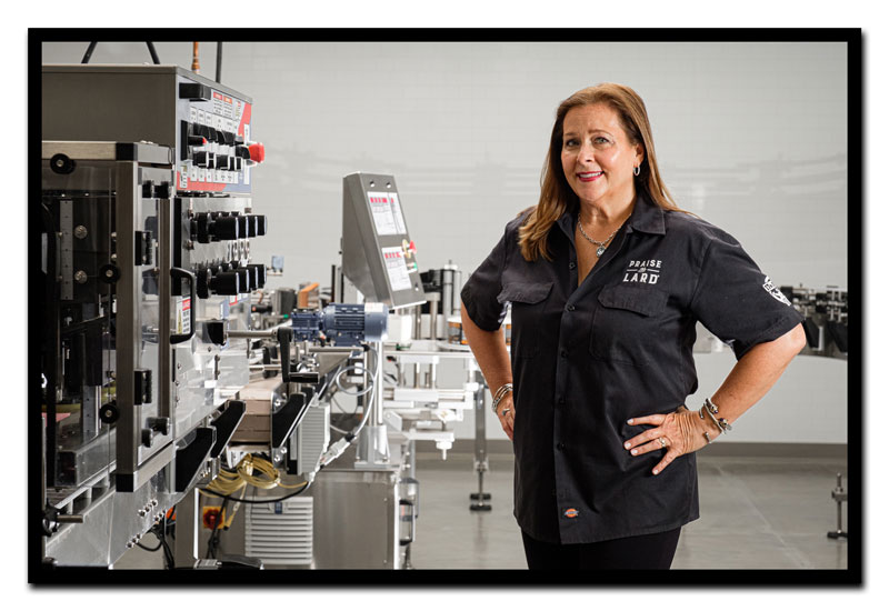 Amy Mills standing in front of Factory at 17th Street bottling machinery