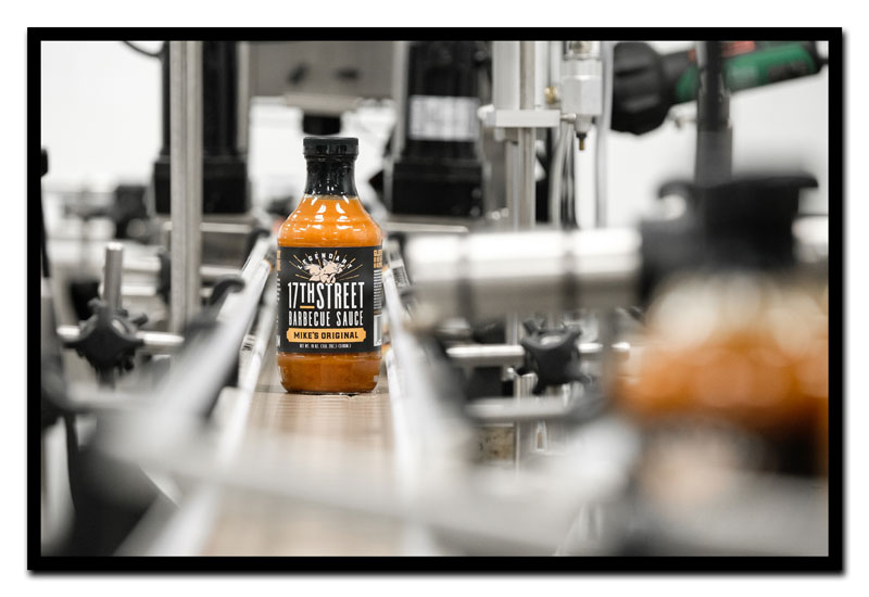 Bottles of 17th Street Barbecue Sauce on bottling conveyor belt.